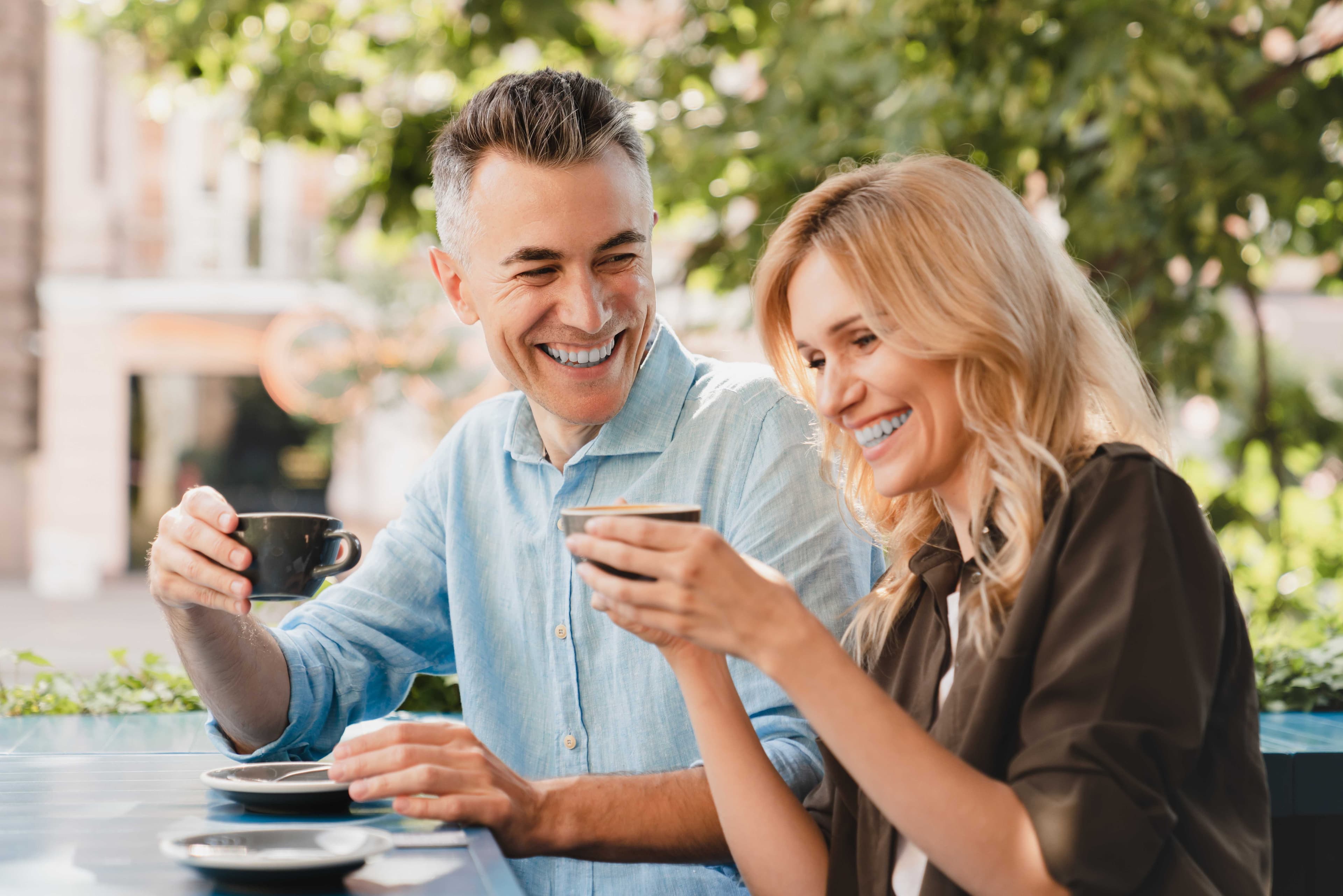 Smiling couple enjoying coffee together outdoors at Livana Fair Lawn in New Jersey.