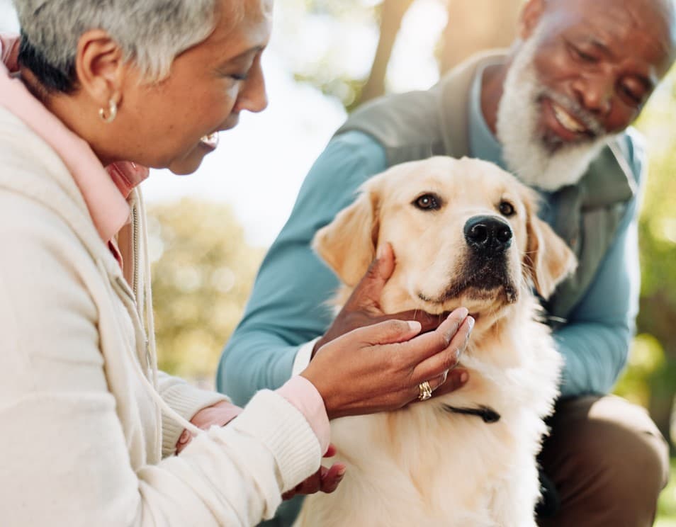 A senior couple smiling while enjoying a relaxed moment with their dog at Livana Fair Lawn in New Jersey.